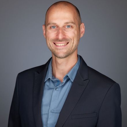 smiling man sitting on gray rock at daytime